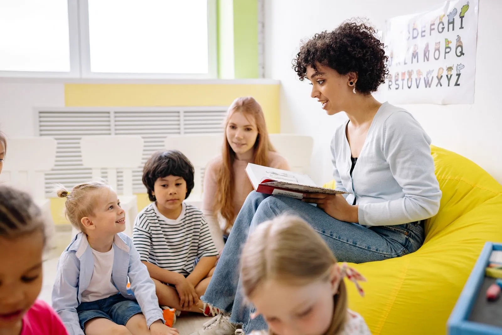 A teacher reads aloud to a circle of young students